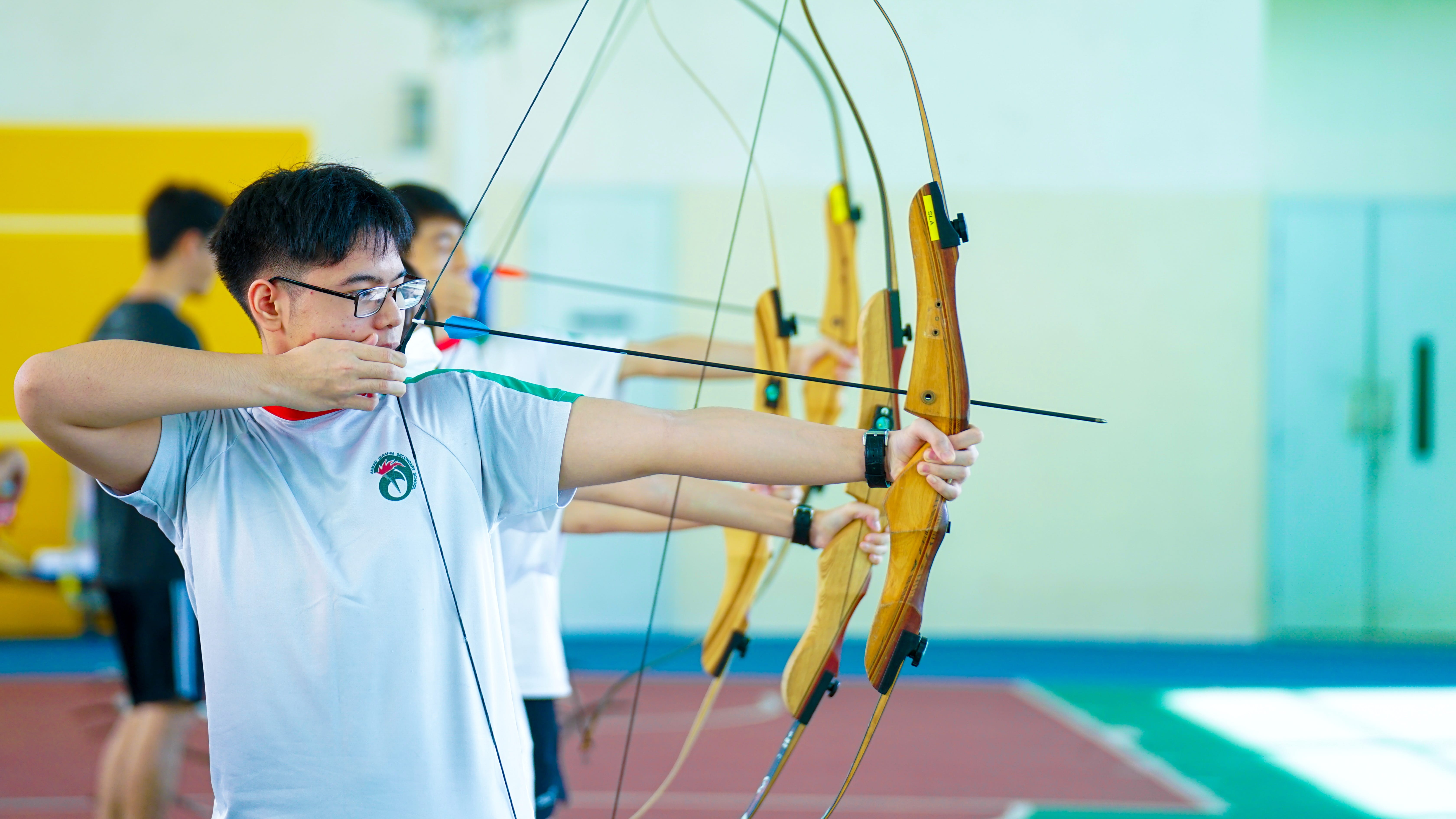 Photo of a students trying out archery displaying courage to try something that is new for them.